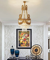 Decorative chandelier hanging above a table with vases and a clock, against a wall with floral artwork.