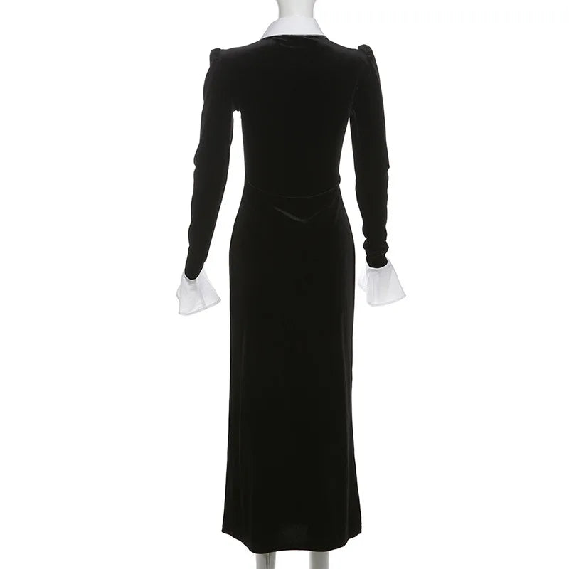 Black velvet dress with white cuffs on a mannequin against a white background