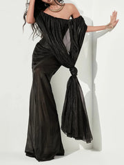 Woman wearing a black off-shoulder outfit with wide-leg pants against a white background