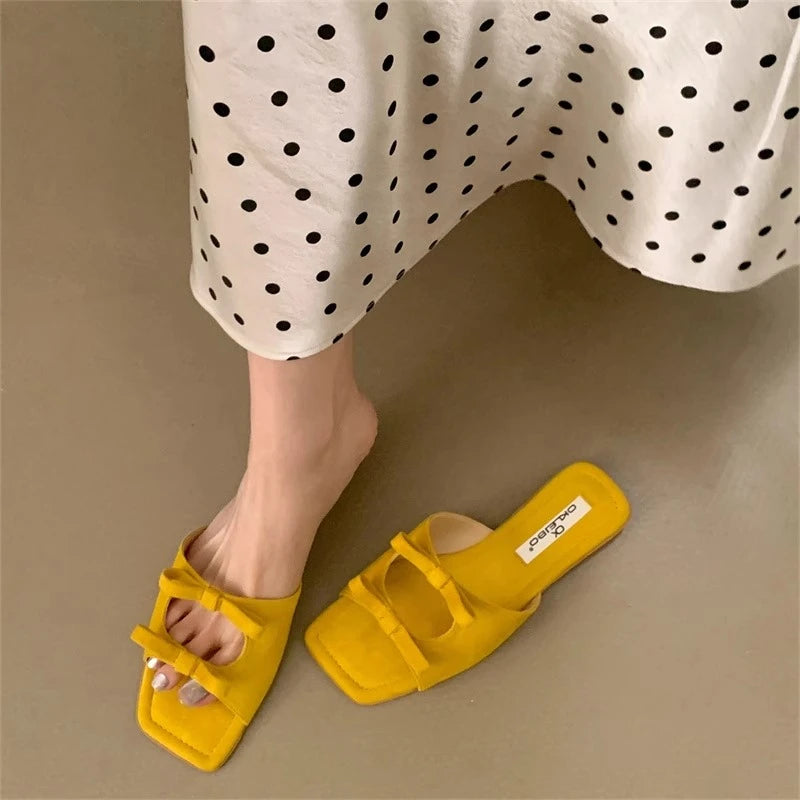 Yellow sandals worn with a polka dot skirt on a beige background