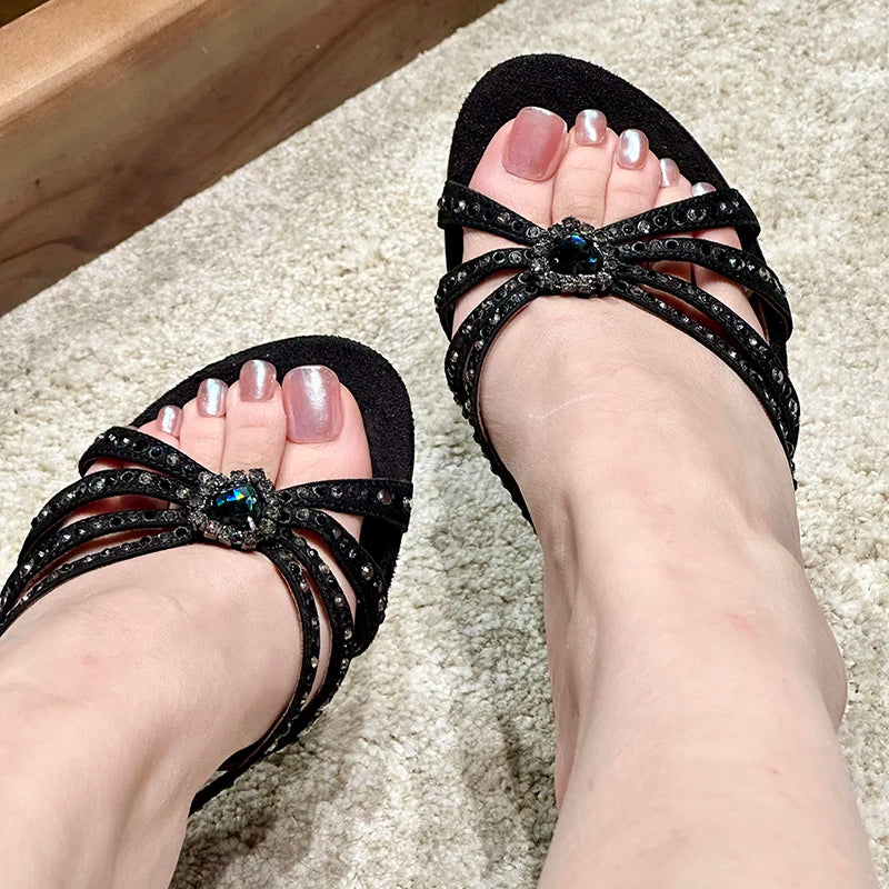 Close-up of feet wearing black embellished stiletto heeled sandals.