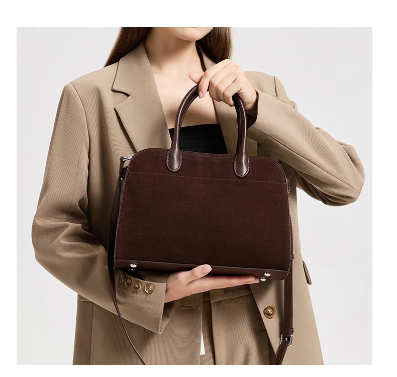 Person holding a brown leather handbag against a neutral background