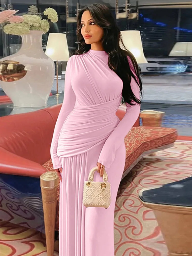 Woman in a pink dress holding a handbag in an indoor setting with decorative elements.