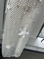 Decorative fishnet curtain with starfish and shell patterns in a room setting.