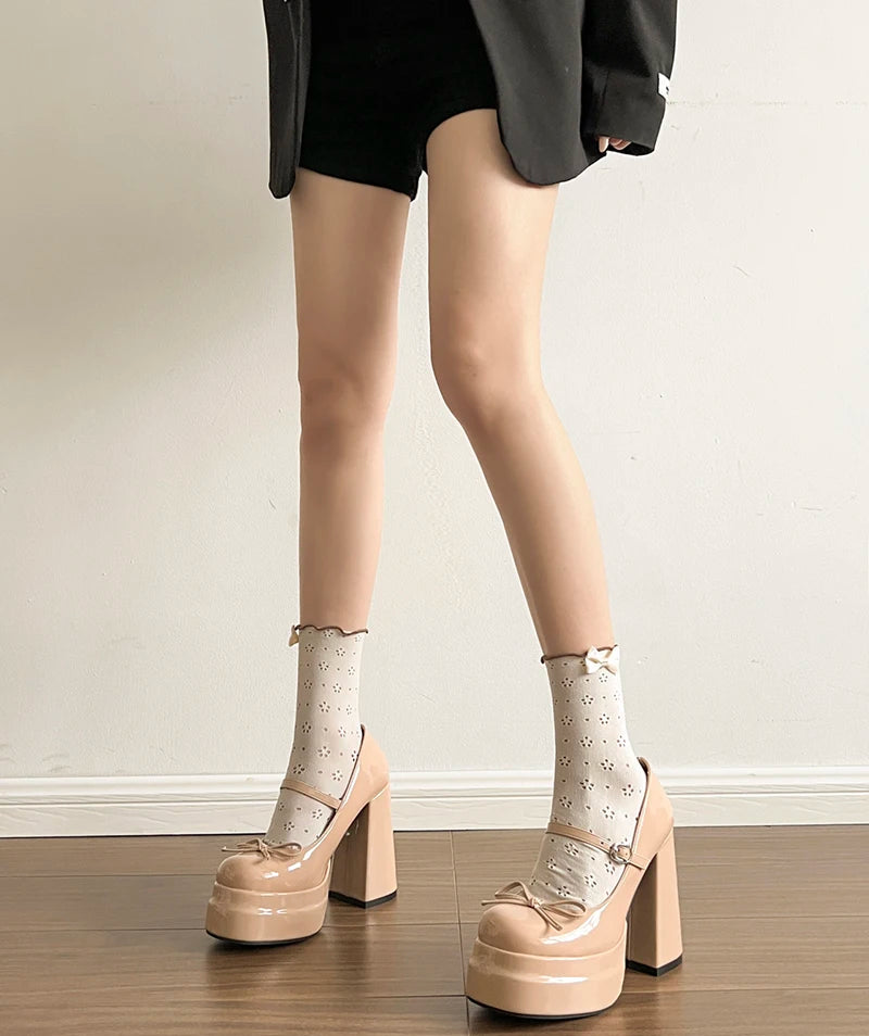 Person wearing beige platform shoes and patterned socks on a plain background