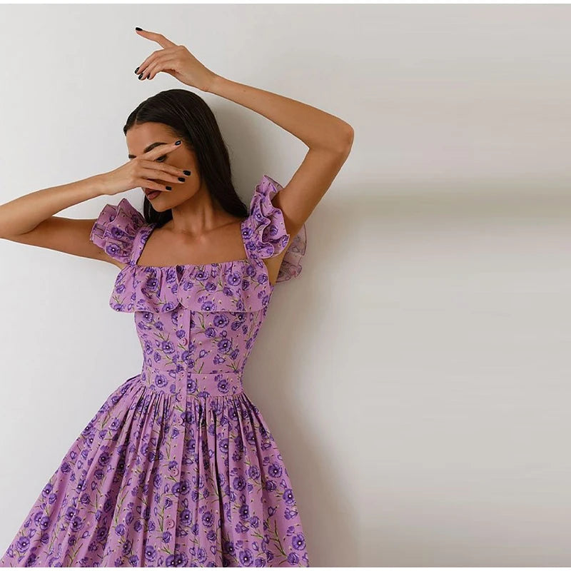Woman wearing a purple floral dress against a plain background