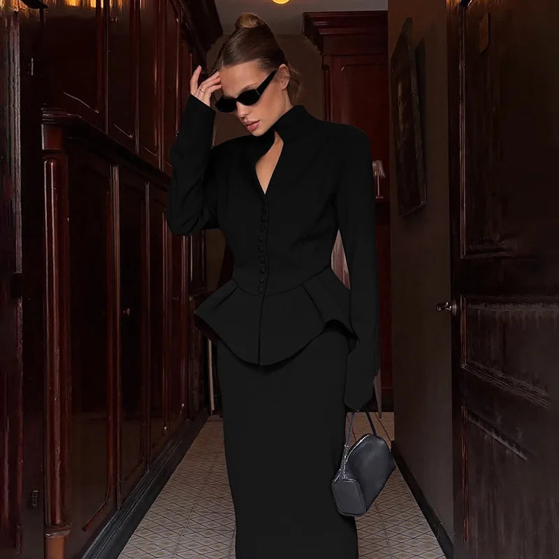 Woman in a black outfit walking through a dimly lit hallway.