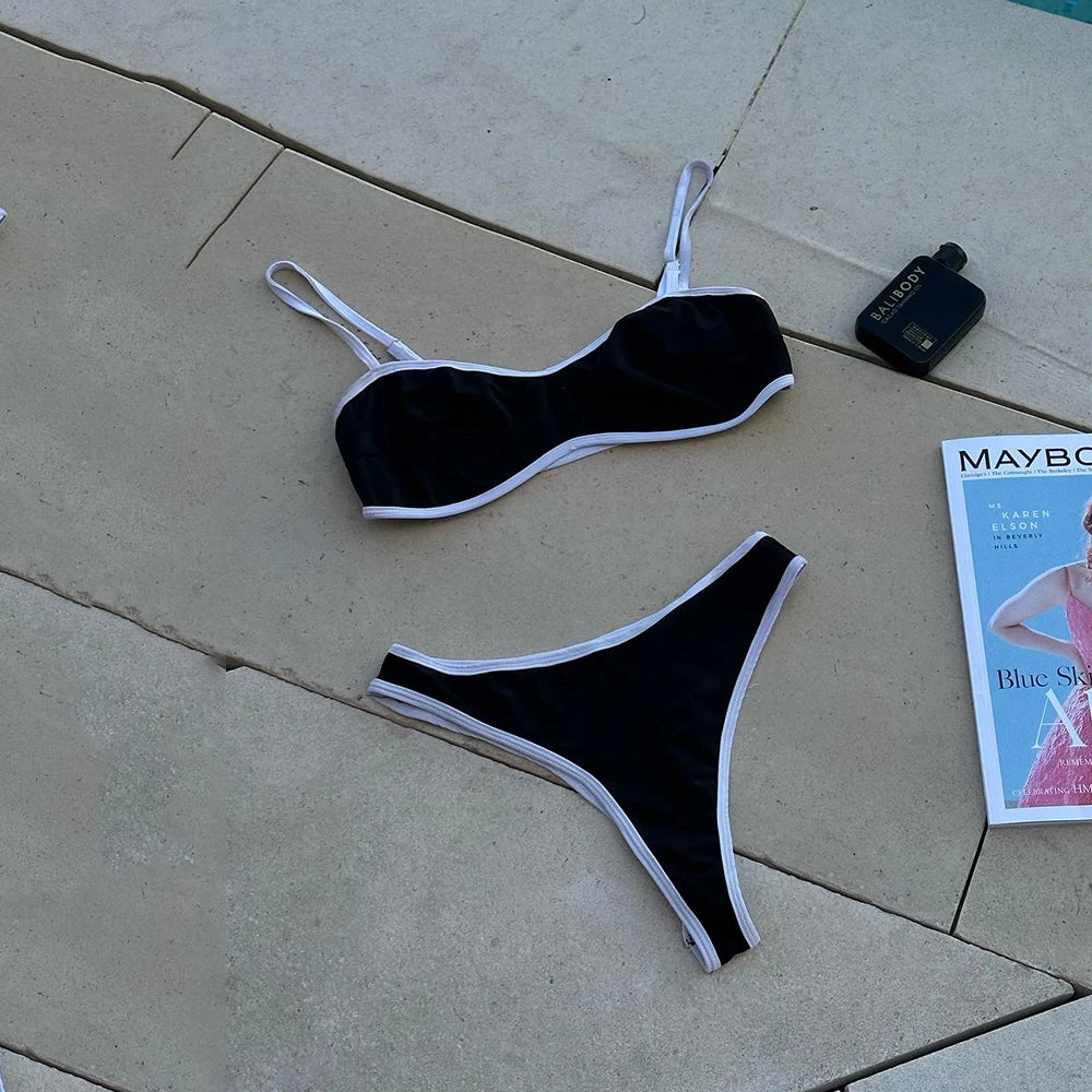 Flat lay of a black and white contrast trim bikini set with accessories.