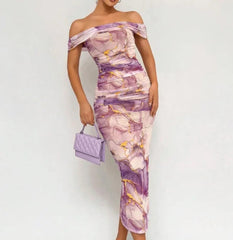 Woman wearing a floral off-shoulder dress with a matching handbag on a white background