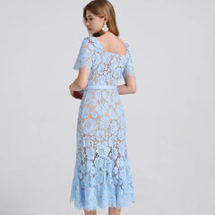 Woman wearing a light blue lace dress on a gray background