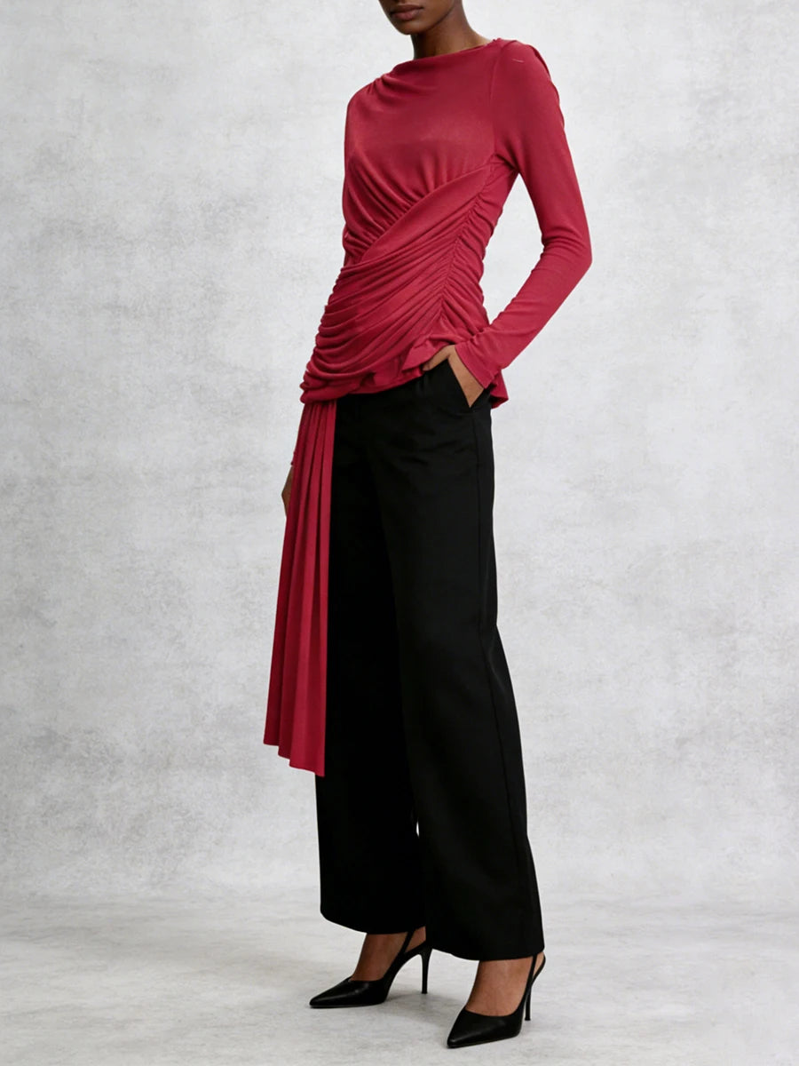 Person wearing a red long-sleeve top and black pants on a light gray background