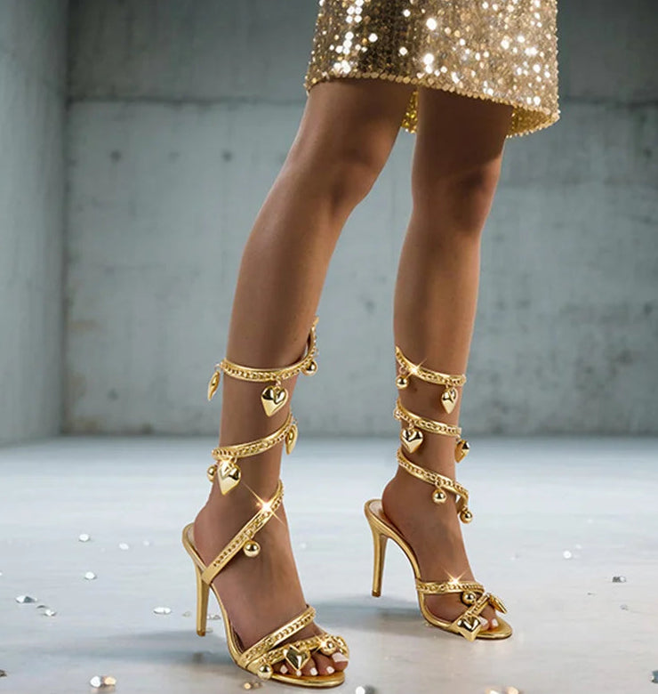Gold chain wrap stiletto sandals on a model's feet