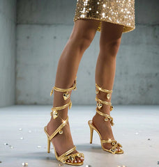 Gold chain wrap stiletto sandals on a model's feet
