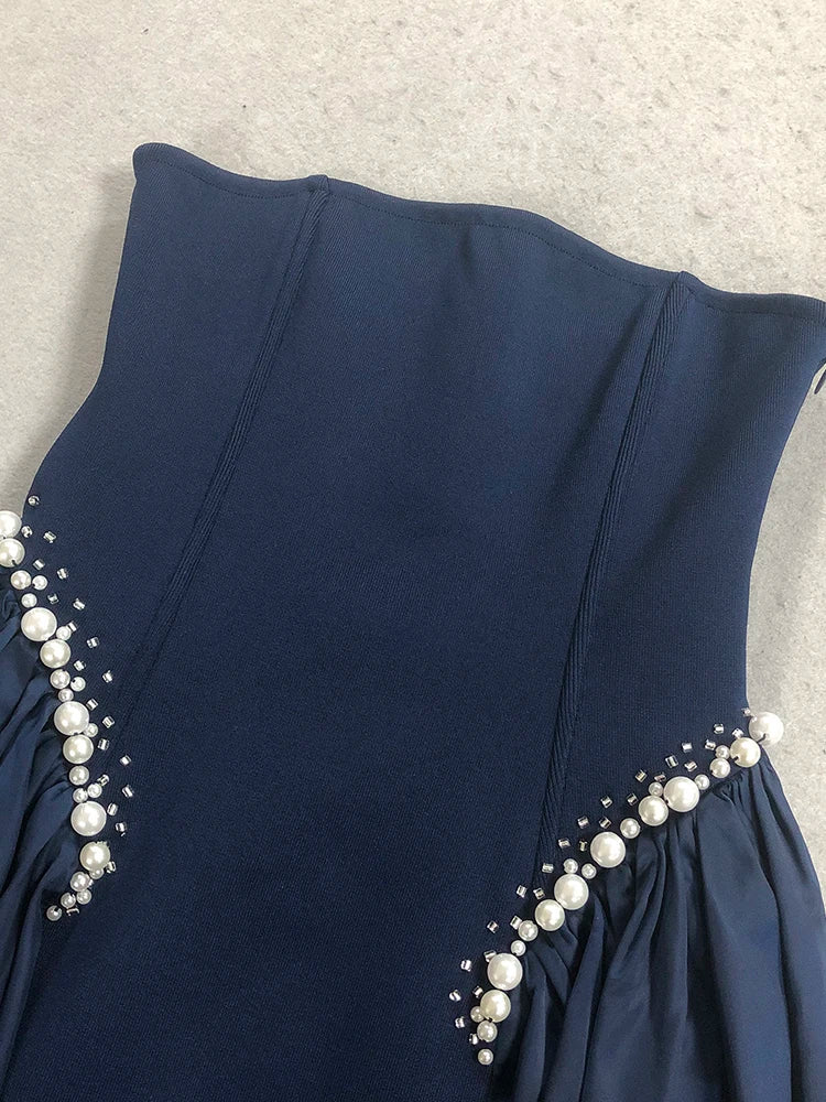 Navy blue dress with pearl embellishments on a neutral background