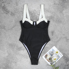 Flat lay of a black one-piece monokini with white contrast trim.