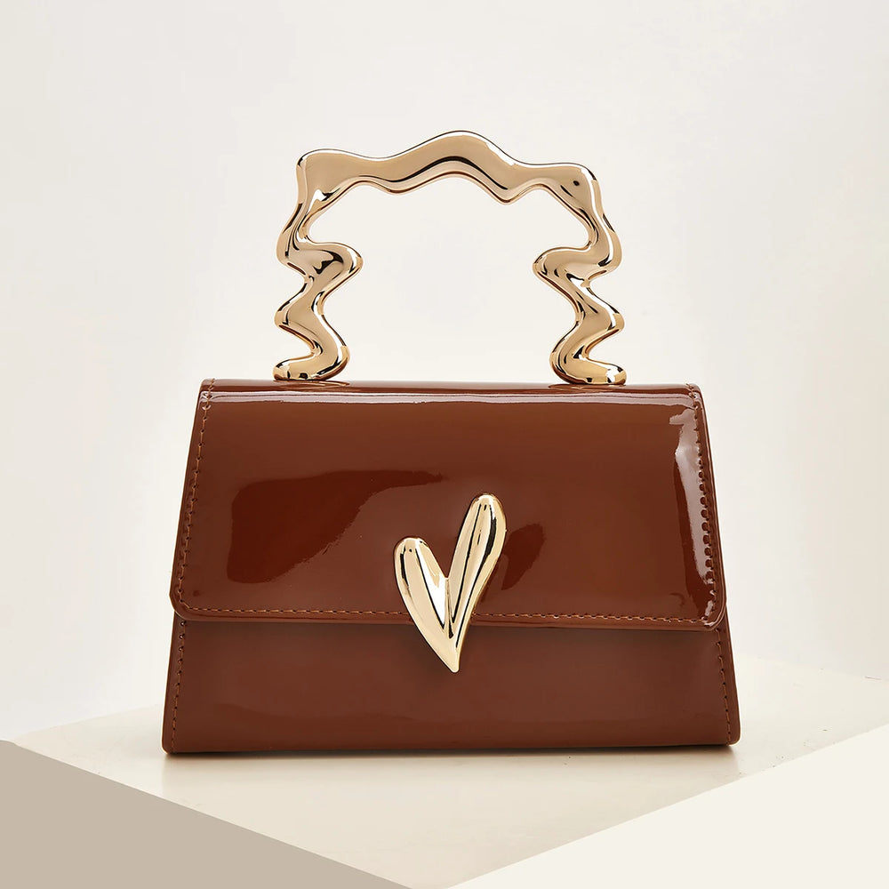 Brown patent leather evening bag with a sculpted gold heart handle.