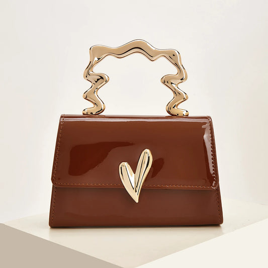 Brown patent leather evening bag with a sculpted gold heart handle.