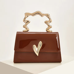 Brown patent leather evening bag with a sculpted gold heart handle.