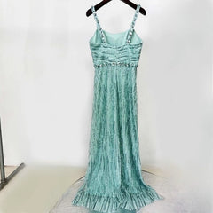 Teal dress with beaded details on a hanger against a white background
