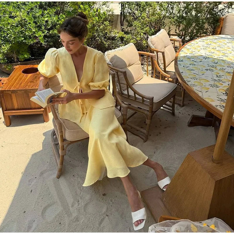 Woman in a yellow outfit reading a book on a patio