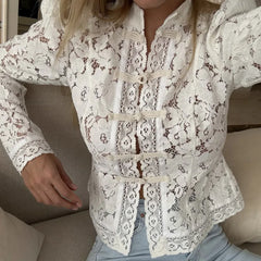 White lace blouse worn by a person sitting on a couch.