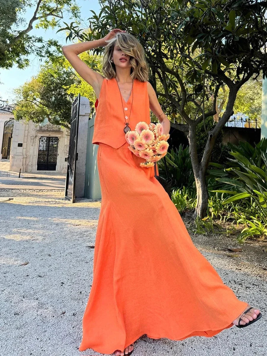 Woman in an orange dress holding a bouquet of flowers outdoors.