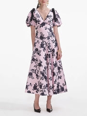 Woman wearing a pink dress with black floral pattern on a white background