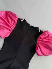 Black dress with pink sleeves and hem on a gray background