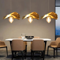 A cozy Dining Table illuminated by a brass lotus leaf pendant light creating a tranquil atmosphere.