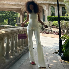 Woman in a white outfit holding a purple handbag in an outdoor setting.