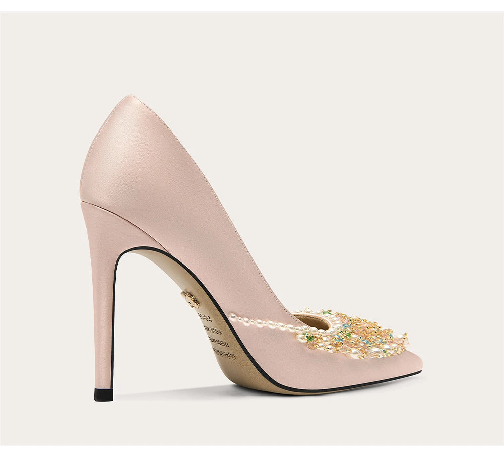 Pink high-heeled shoe with embellishments on a light gray background