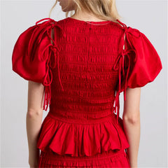 Woman wearing red ruffled smocked crop top with puff sleeves and fitted waist