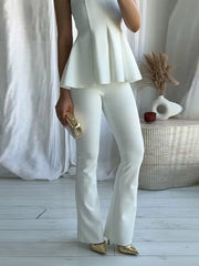 Person wearing a white outfit with gold shoes in a minimalistic setting