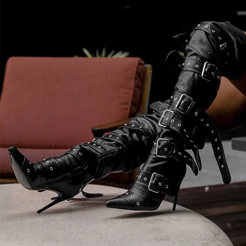 Black studded high-heeled boots on a gray surface with a blurred background