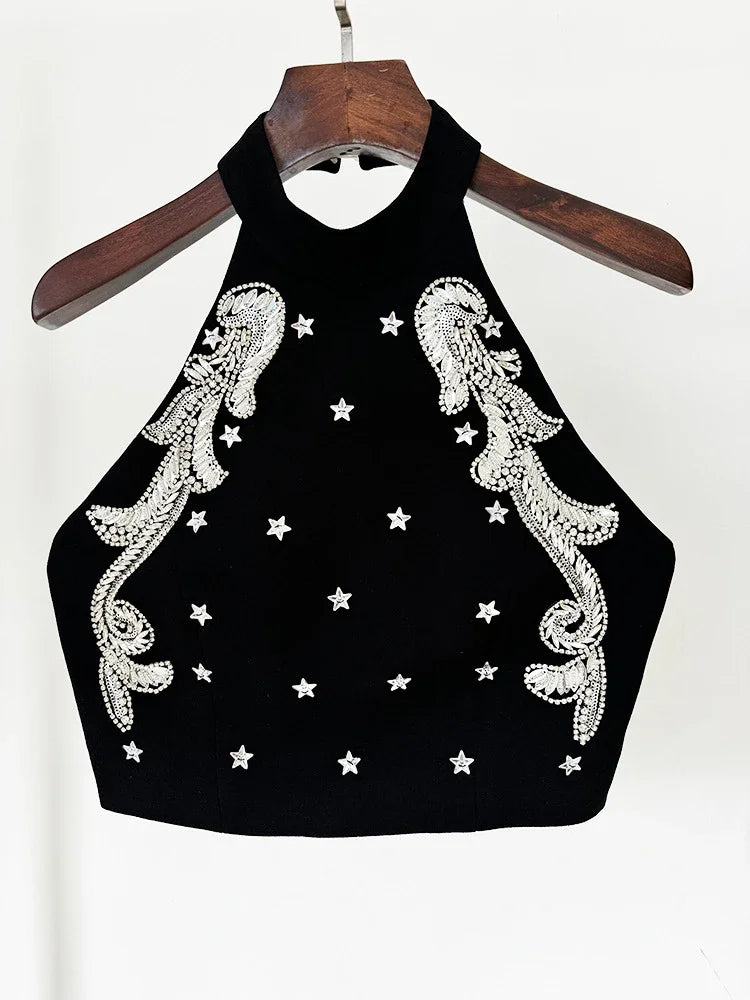 Black crop top with white embroidery and star patterns on a hanger against a white background