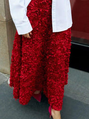 Red textured skirt worn with a white top against a neutral background