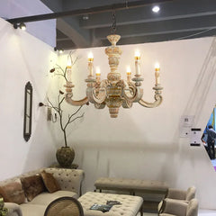 Vintage Roman pillar chandelier with wood carvings and Murano-style glass accents, hanging in a luxurious living room. Golden Atelier 4