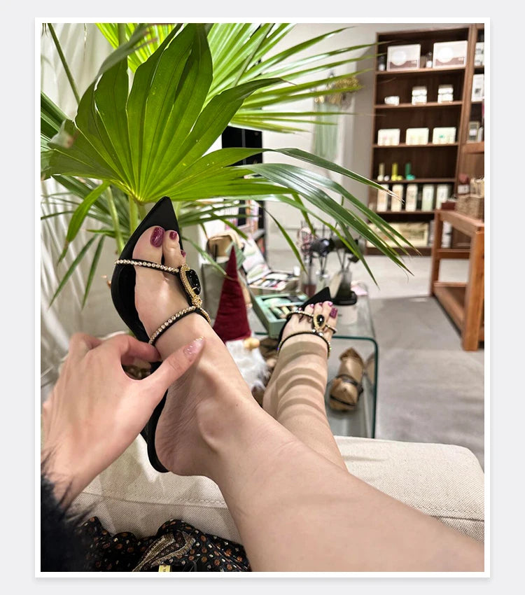 Person wearing high-heeled shoes with decorative elements, sitting in a room with plants and furniture.