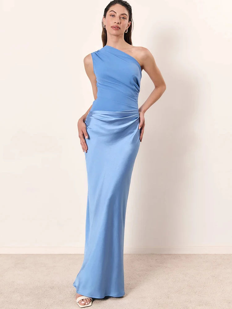 Woman wearing a light blue one-shoulder dress against a plain background