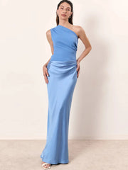 Woman wearing a light blue one-shoulder dress against a plain background