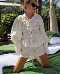 Woman in a white outfit sitting on a green surface with a blurred background