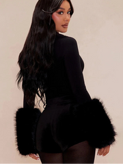 Woman wearing a black outfit with feathered sleeves against a beige background