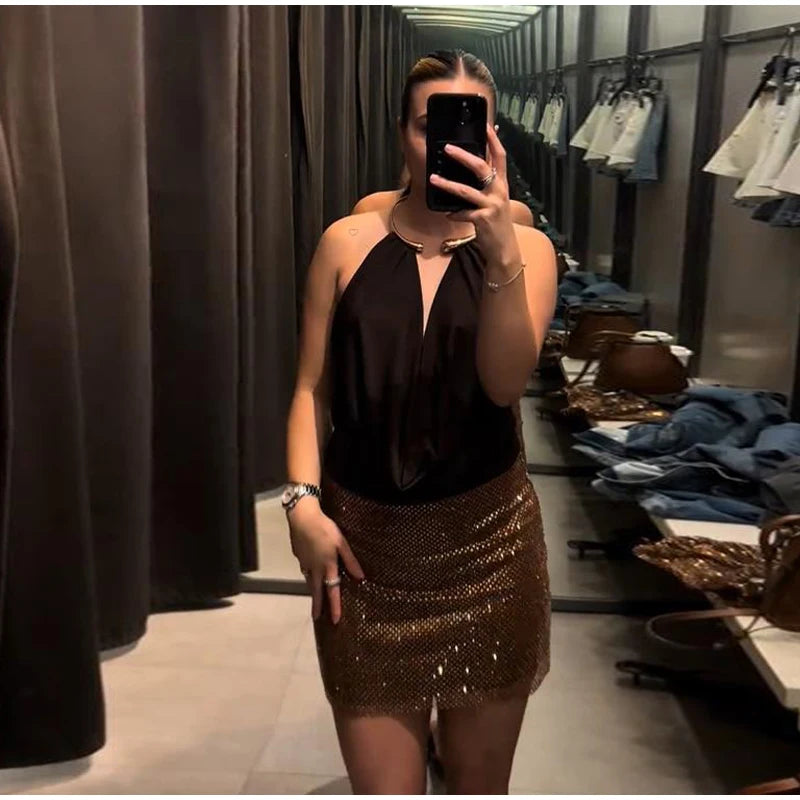 Person taking a mirror selfie wearing a black top and gold sequin skirt in a clothing store.