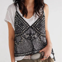 Person wearing a black sequin top over a white shirt on a plain background