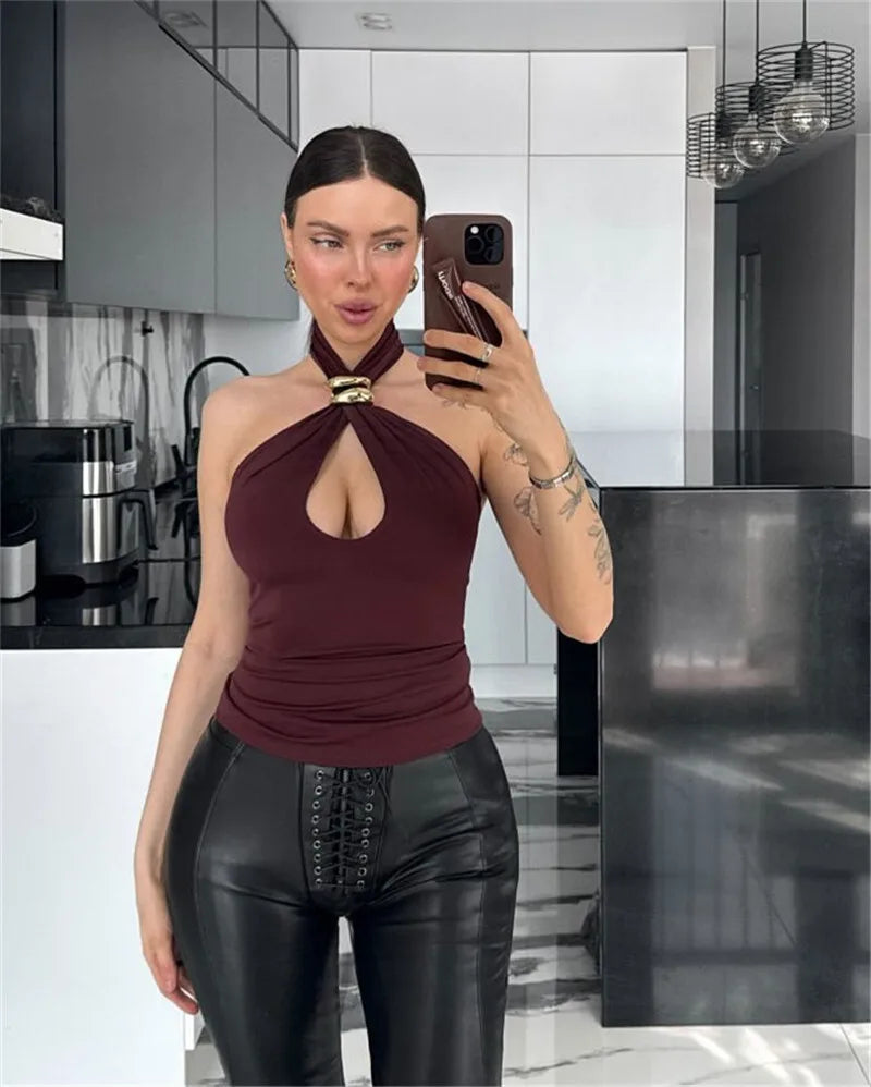 Woman taking a mirror selfie in a modern kitchen wearing a burgundy top and black pants.