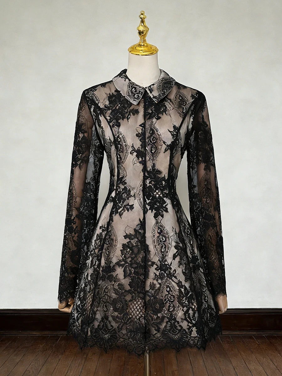 Black lace dress on a mannequin against a plain background