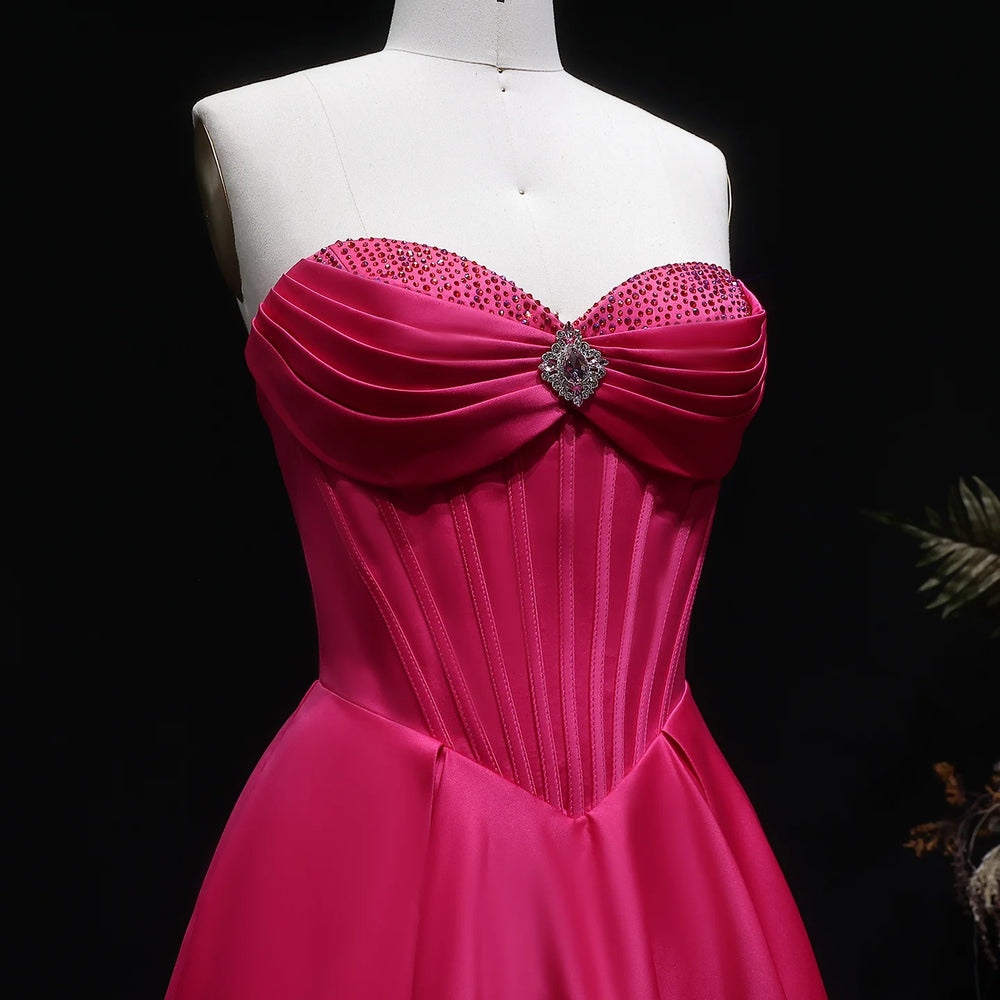 Pink evening gown with embellishments on a mannequin against a dark background