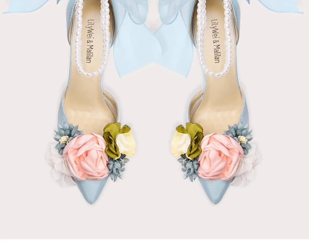 Pair of high-heeled shoes with floral decorations on a light background