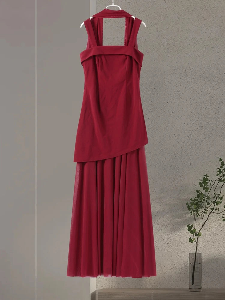 Red dress on a hanger against a neutral wall with a plant in the corner.