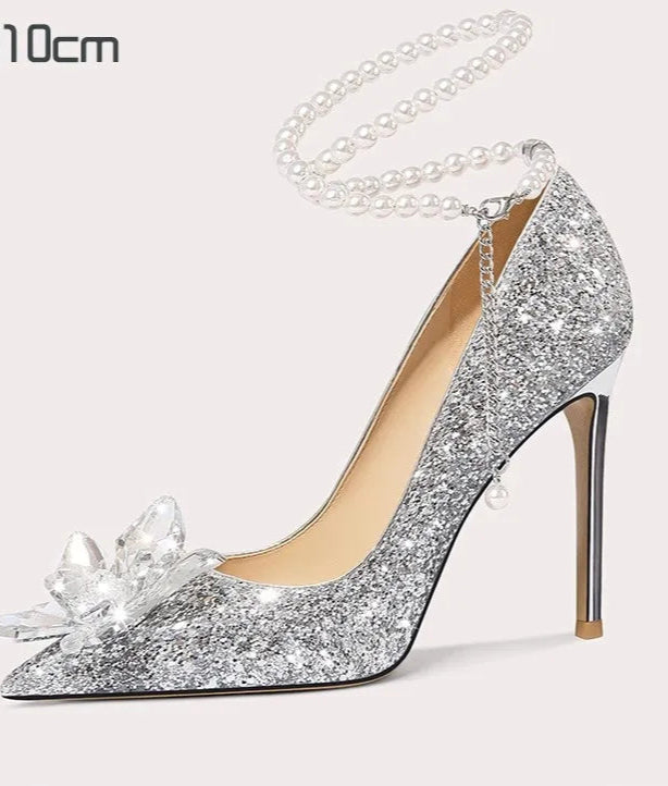 Silver glitter high-heeled shoe with a decorative flower on a white background